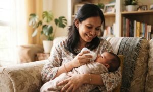 Mother feeding newborn baby with a wide-neck nursing bottle