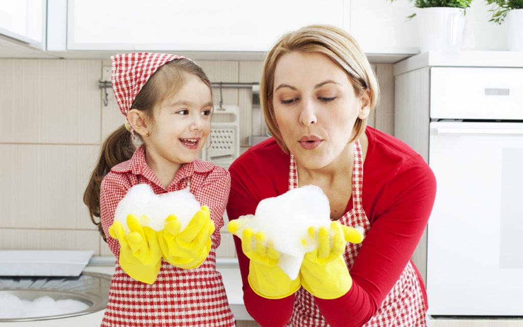 Mother and daughter having fun blowing foam in the kitchen