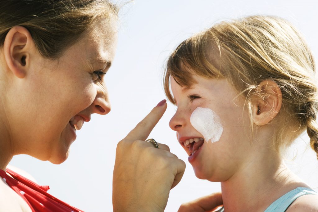 mother and daughter applying sunscreen